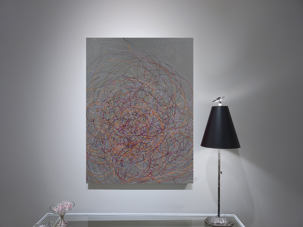 "The Favorite Place Is in the Middle of a Song" hanging above a table and next to a lamp by Charles H. Reinike III